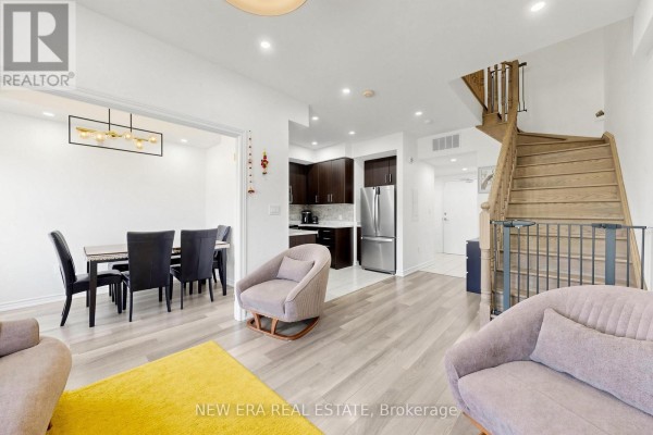 Open concept living space with dining room, kitchen, and wooden staircase. - 216 - 3865 Major Mackenzie Drive W, Vaughan