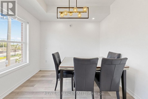 Dining room with dark table and chairs, and a large window overlooking the street. - 216 - 3865 Major Mackenzie Drive W, Vaughan