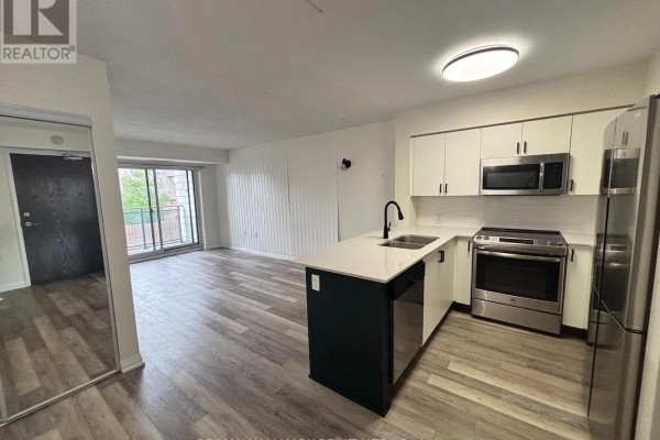 Open concept kitchen with white cabinets, island, and stainless steel appliances. - 216 - 40 Via Rosedale Avenue, Brampton