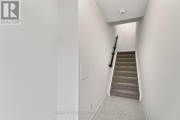 Interior staircase with carpeted steps, black railing, and white walls. - 216 - 581 Takamose Private, Ottawa