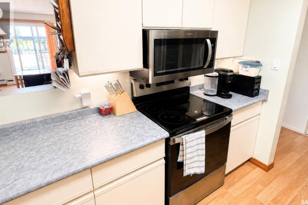 Close-up of apartment kitchen counter with stainless steel stove, microwave, and coffee maker. - 216 3420 Park Street, Regina