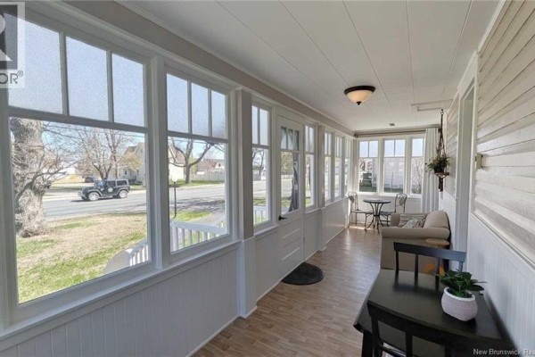 Sunroom with large windows, a seating area, and pale wood paneling. - 216 Boul. Saint-pierre O, Caraquet