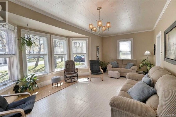 Living room with multiple sofas, a rocking chair, and a bay window. - 216 Boul. Saint-pierre O, Caraquet