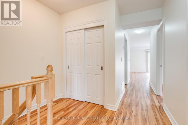 Interior hallway with light wood laminate flooring, white trim, and double sliding doors. - 216 Carillon Street, Ottawa