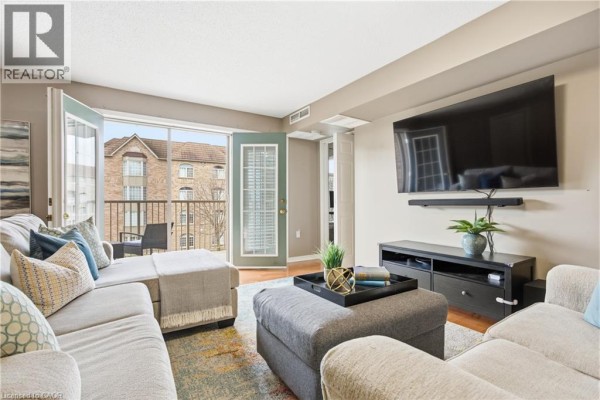 Open kitchen area with white cabinetry, granite countertops, and a view into the living space. - 216 Plains Road W Unit# F304, Burlington