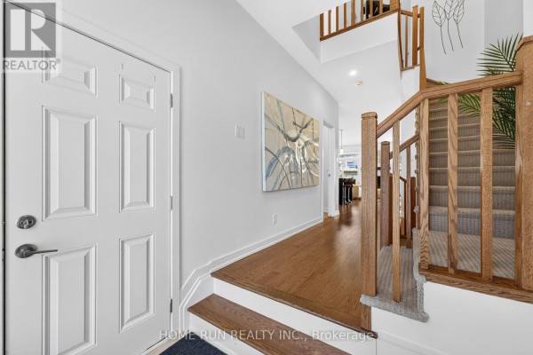 Interior foyer with white doors, hardwood flooring, and a carpeted staircase. - 216 Trumpeter Grove, Ottawa