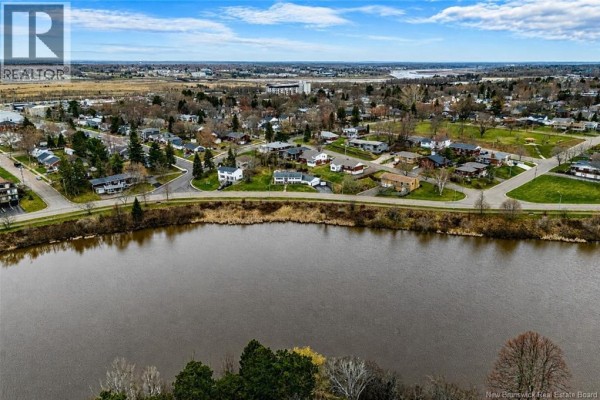 Aerial view of the residential area bordering a wide river, with houses and trees. - 216 Westmount Boulevard, Moncton