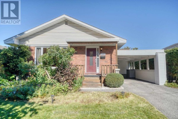Front view of the house with a driveway, carport, and manicured bushes. - 2161 Rushton Road, Ottawa
