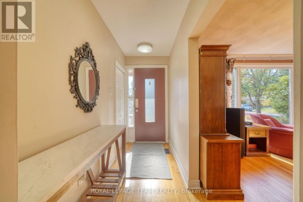 Interior hallway with a console table, mirror, and door leading to living area. - 2161 Rushton Road, Ottawa