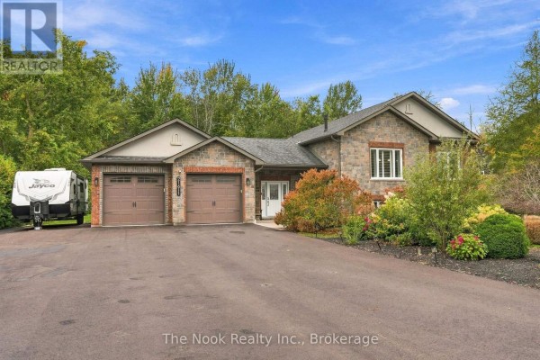 Front exterior of a stone and brick house with a double garage and paved driveway. - 21611 Loyalist Parkway, Prince Edward County