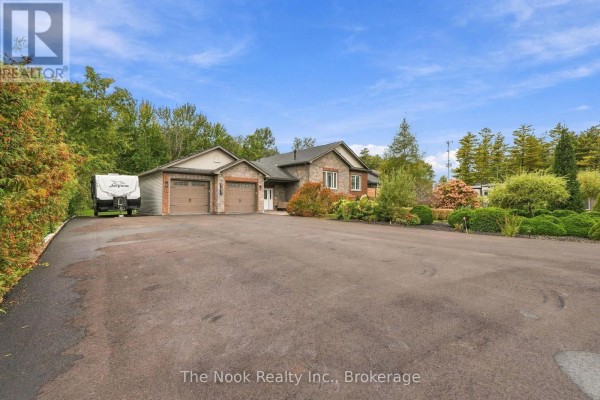 Paved driveway leading to a stone and brick house with a double garage. - 21611 Loyalist Parkway, Prince Edward County