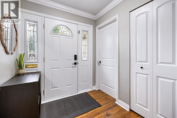 Interior view of the foyer with white double doors, a dark entryway table, and wood flooring. - 21678 Mountainview Crescent, Maple Ridge