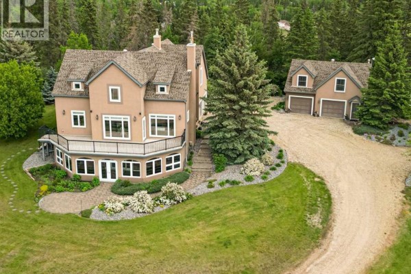 Gravel driveway leading to the house, flanked by trees and stone pillars. - 217, 27111 Highway 597, Rural Lacombe County