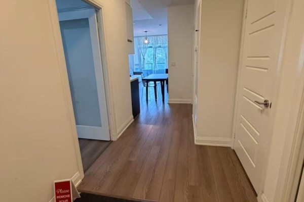 View of a hallway with wood flooring, doors, and an opening to the living area. - 217 - 15 Water Walk Drive, Markham