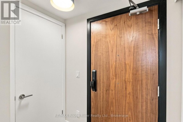 Hallway view of a modern apartment entrance with a wooden door and a white door. - 217 - 201 Brock Street S, Whitby