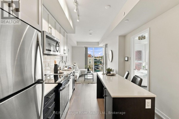 View of the kitchen island and living space with a window showing a city view. - 217 - 201 Brock Street S, Whitby