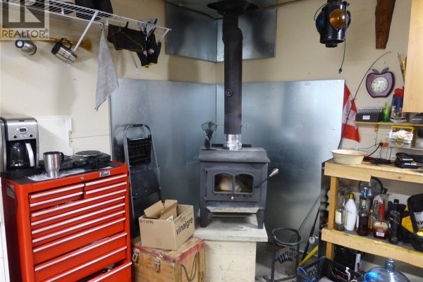 Interior of a workshop featuring a wood stove and storage shelves - 217 & 221 Birch Drive, Turtle View