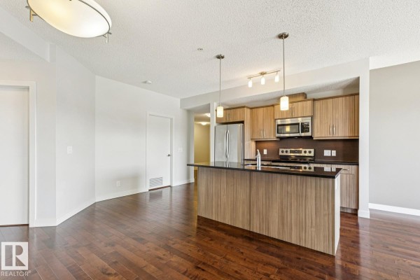 View of kitchen island and cabinets from living room area with hardwood floors. - #217 10523 123 St Nw, Edmonton