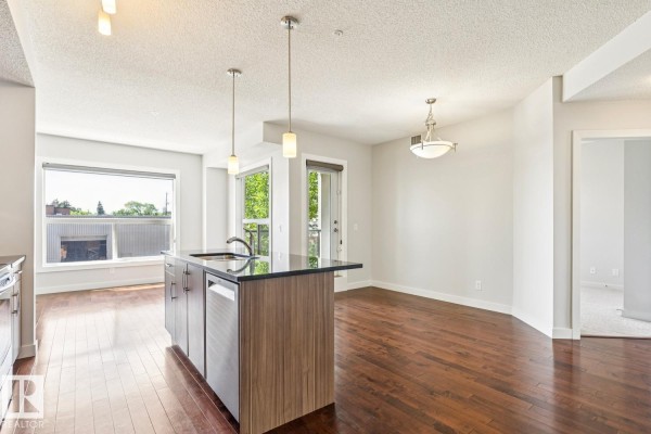 Kitchen island with stainless steel dishwasher and sink in a bright, open living area. - #217 10523 123 St Nw, Edmonton