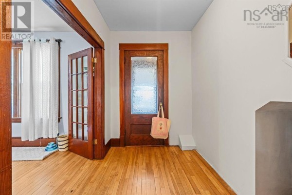 Interior hallway with wooden floors, a wooden door with frosted glass, and white walls. - 217-219 Albert Street, New Glasgow