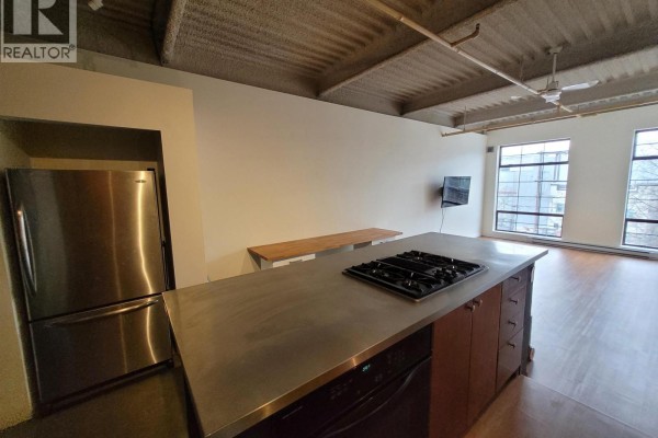 Kitchen with stainless steel refrigerator and gas range on concrete counter. - 217 237 E 4th Avenue, Vancouver