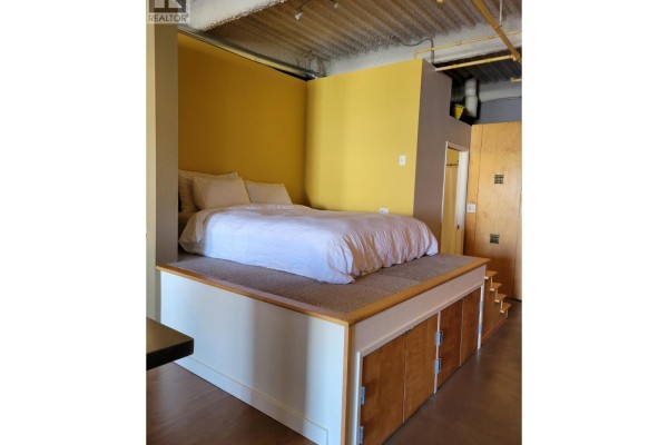 Loft bed with storage drawers below and yellow accent wall. - 217 237 E 4th Avenue, Vancouver