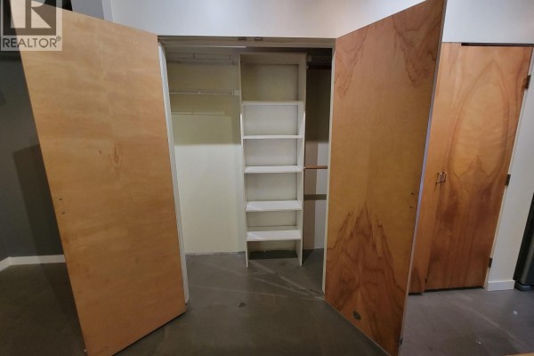 Open closet with white shelves and wooden doors. - 217 237 E 4th Avenue, Vancouver