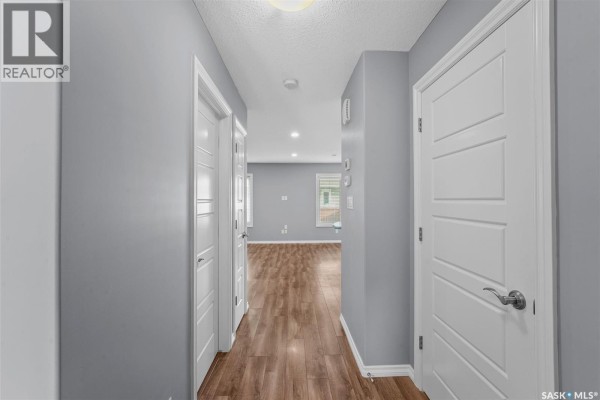Kitchen with stainless steel appliances, grey quartz countertops, and island with seating. - 217 4002 Sandhill Crescent, Regina