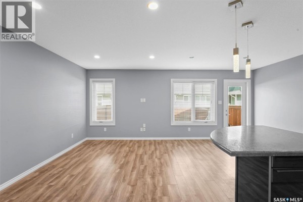 Open concept living, dining, and kitchen area with light grey walls and laminate flooring. - 217 4002 Sandhill Crescent, Regina