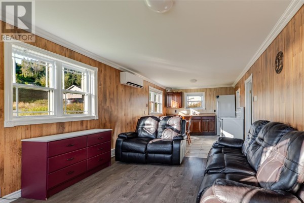 Living area with two black leather couches, wood-paneled walls, and a red dresser. - 217 Admirals Cove Road, Admirals Cove