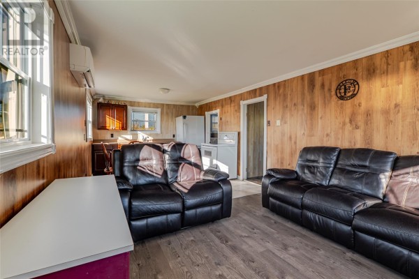 Interior view of the living area with two couches, wood paneling, and windows. - 217 Admirals Cove Road, Admirals Cove