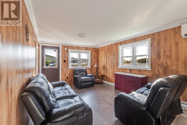 Living room with leather seating, wood walls, a door, and windows overlooking a landscape. - 217 Admirals Cove Road, Admirals Cove