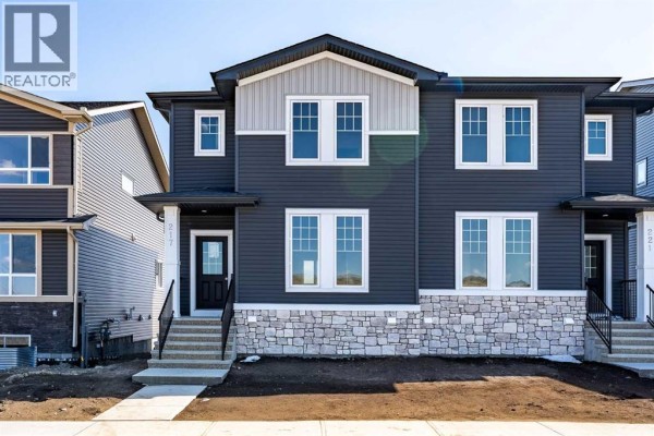 Front view of a modern dark grey duplex with contrasting white and stone accents. - 217 Bridgeport Gate, Chestermere