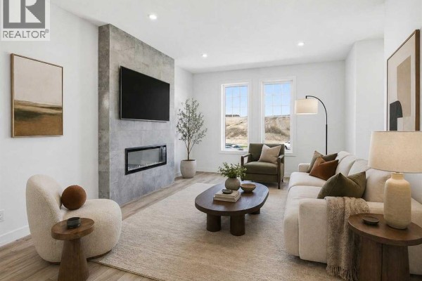 Living room with a fireplace, mounted television, sofa, armchair, coffee table, and two windows. - 217 Bridgeport Gate, Chestermere