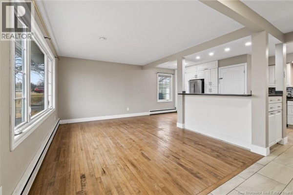 A spacious living room with hardwood floors and an open view to the kitchen. - 217 Canterbury Avenue, Riverview