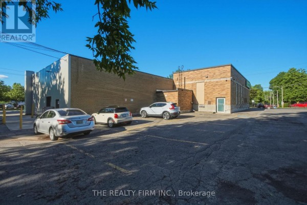 Rear and side exterior view of the commercial building with a parking lot and trees. - 217 Wharncliffe Road S, London South