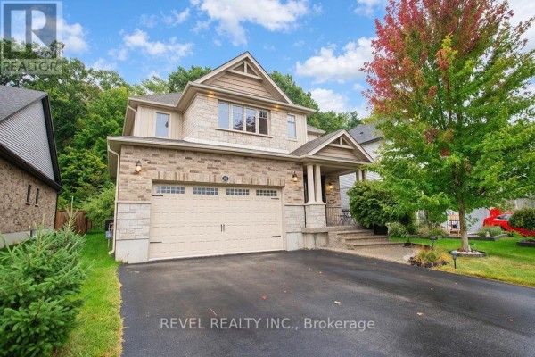 Side view of the house exterior showing the front entrance, driveway, and landscaping with a colourful tree. - 217 Woodway Trail, Norfolk