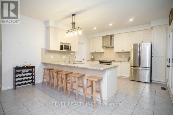 Modern kitchen with white cabinets, granite countertops, an island with pendant lights, and stainless steel appliances. - 217 Woodway Trail, Norfolk
