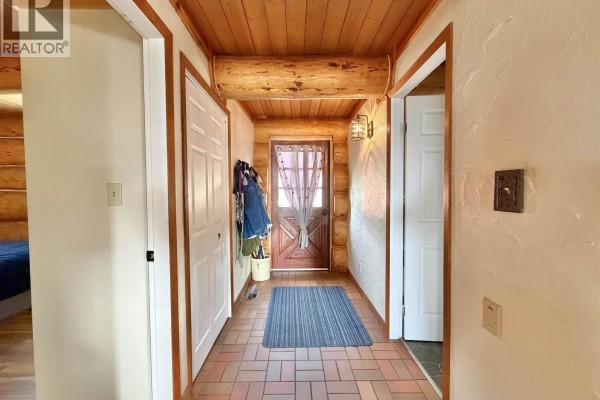 Interior hallway with wood paneling, white doors, and a tiled floor. - 2175 White Road, Williams Lake
