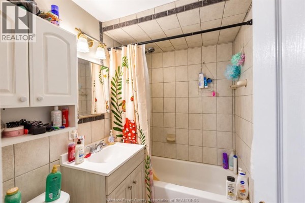 Bathroom with beige tile, vanity with sink, mirror, and shower with curtain. - 2176 Mcdougall, Windsor