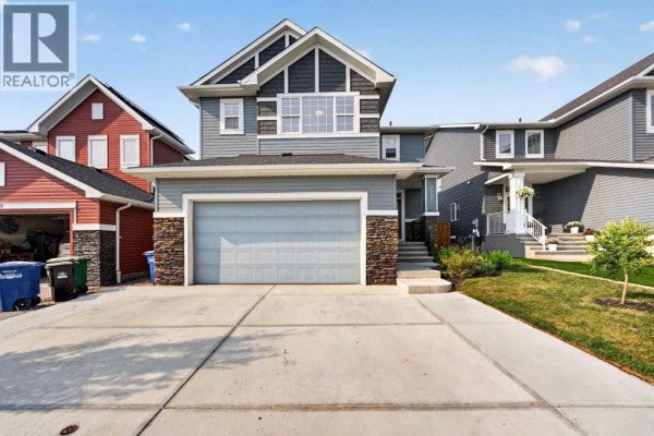 Front exterior view of a two-story house with a grey siding and stone accents. - 2177 Ravensdun Crescent Se, Airdrie