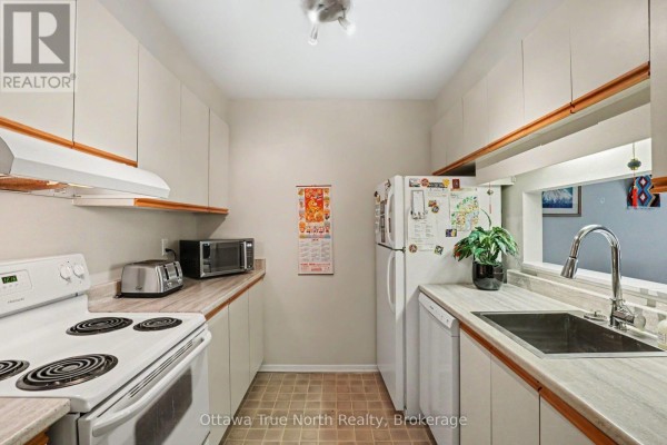 Kitchen with white appliances, beige cabinets, and light countertops. - 218 - 212 Viewmount Drive, Ottawa