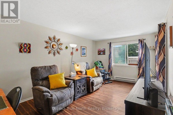 Living room with two recliners, a television, and a large window. - 218 - 212 Viewmount Drive, Ottawa