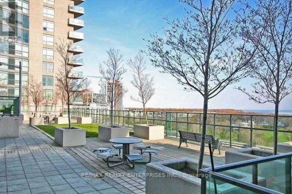 Outdoor patio with tables, benches, and planters with bare trees, overlooking a distant view. - 218 - 231 Fort York Boulevard, Toronto