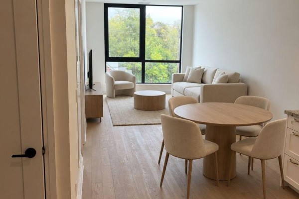 Living and dining area with a sofa, coffee table, round dining table, and chairs by a large window. - 218 - 2788 Bathurst Street, Toronto