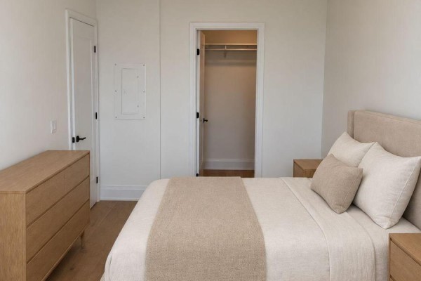 Bedroom with a bed, dresser, and open closet door, showing a bed and nightstands. - 218 - 2788 Bathurst Street, Toronto