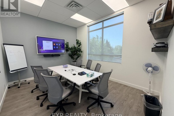 Conference room with a white table, chairs, large monitor, whiteboard, and window. - 218 - 65 Denzil Doyle Court, Ottawa