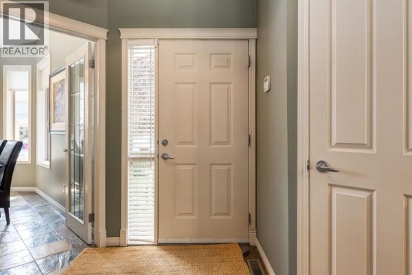 Interior front door with a small window, light green walls, and slate tile flooring. - 218 Springbank Villas Sw, Calgary