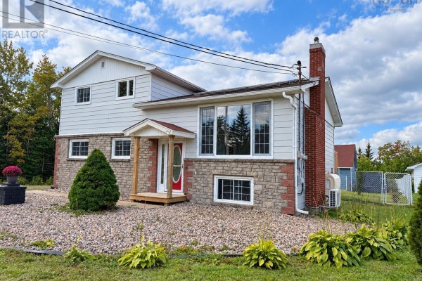 Side view of the house showing stone and vinyl siding, red brick chimney, and gravel landscaping. - 2183 Old Sambro Road, Williamswood