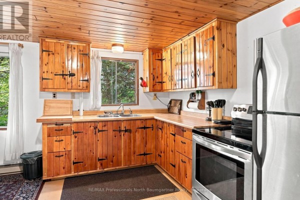 Kitchen featuring knotty pine cabinets, double sink, stainless steel range, and refrigerator with a wood plank ceiling. - 2183 Trapper's Trail, Dysart Et Al